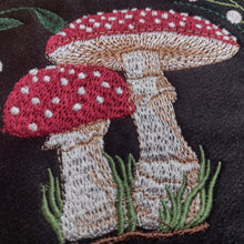 Embroidered design of red and white mushrooms on a dark fabric background
